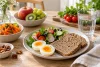 Du pain complet est servi dans un repas varié avec des aliments simples.